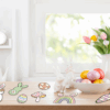 Spring flowers, Easter eggs, and ceramic bunnies on table.