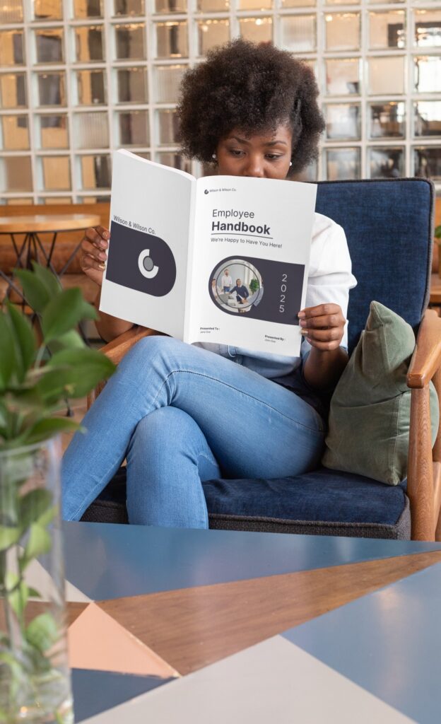 Person reading employee handbook in comfortable chair.