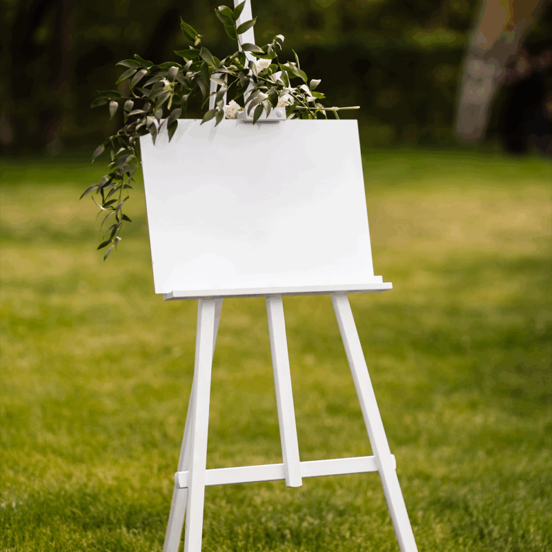Blank easel with greenery on lawn